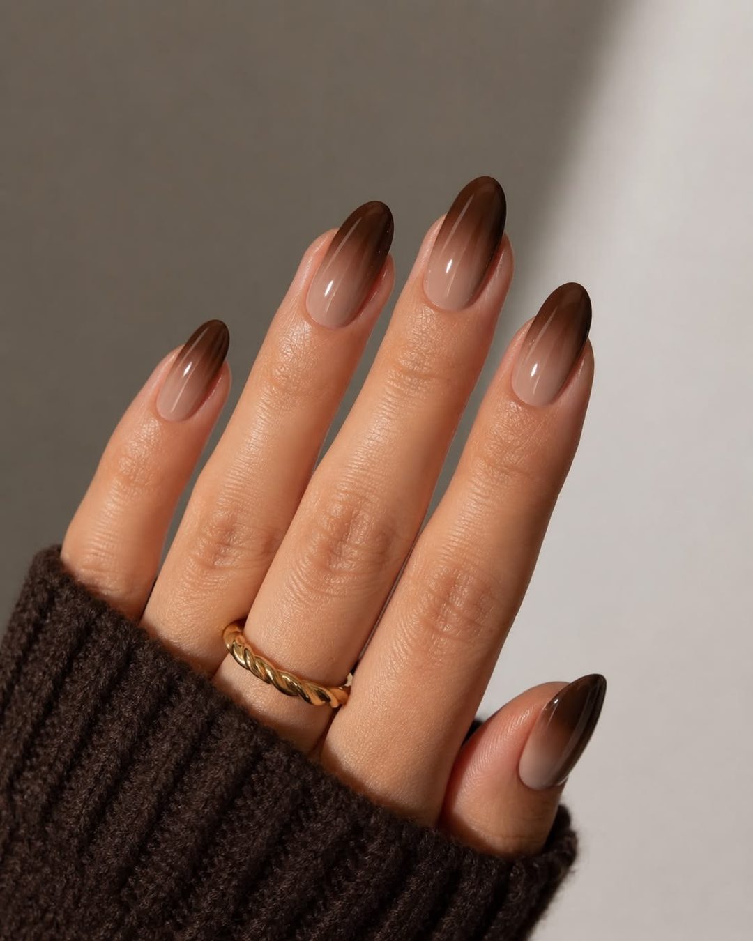 Almond-shaped nails with an ombré from nude to dark chocolate brown