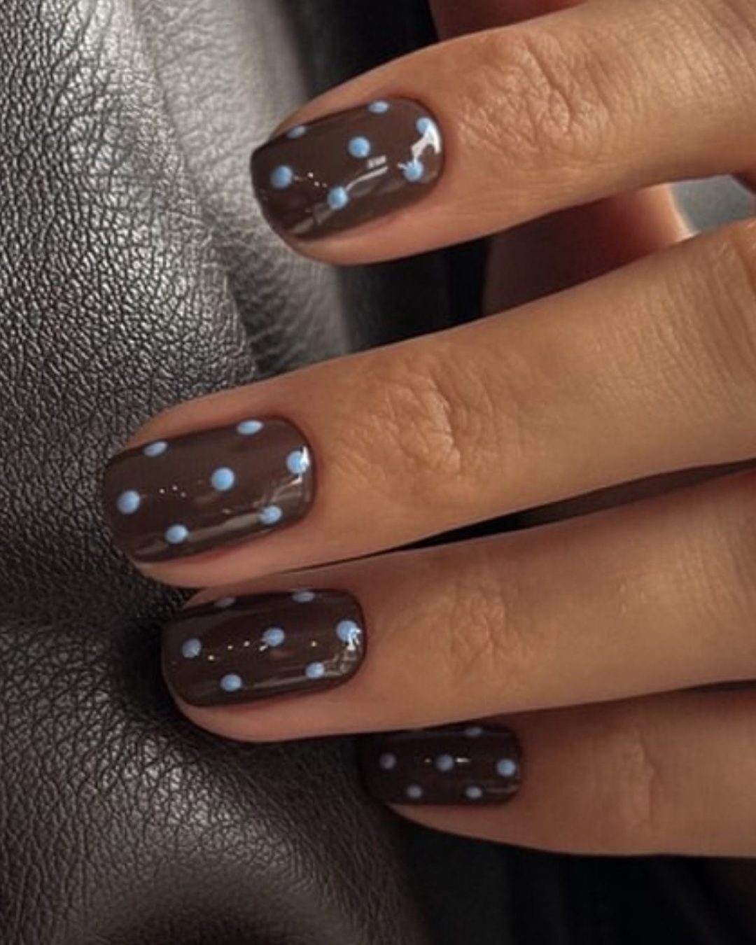 Short nails in dark chocolate brown with small light blue dots